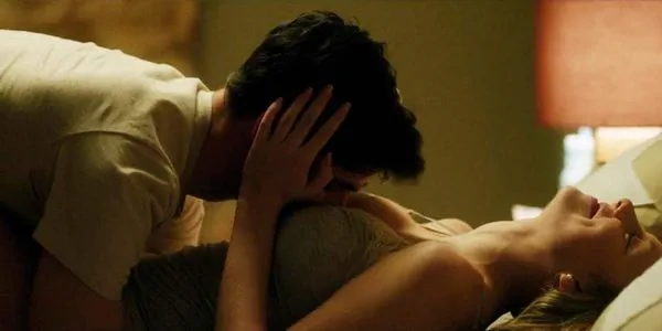 mężczyzna całuje cycki dziewczyny na łóżku