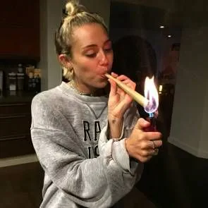 Miley Cyrus menyalakan rokok besar